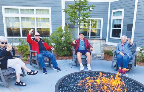 Four people are sitting outside on chairs, enjoying a fire pit. AI generated content